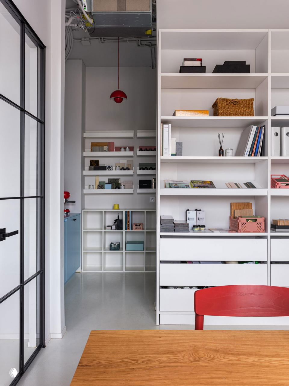 Кухонный уголок и стеллажи офиса DSGN HUB: белые полки, голубые фасады мебели и аккуратно расставленные предметы декора и посуды для рабочего пространства.