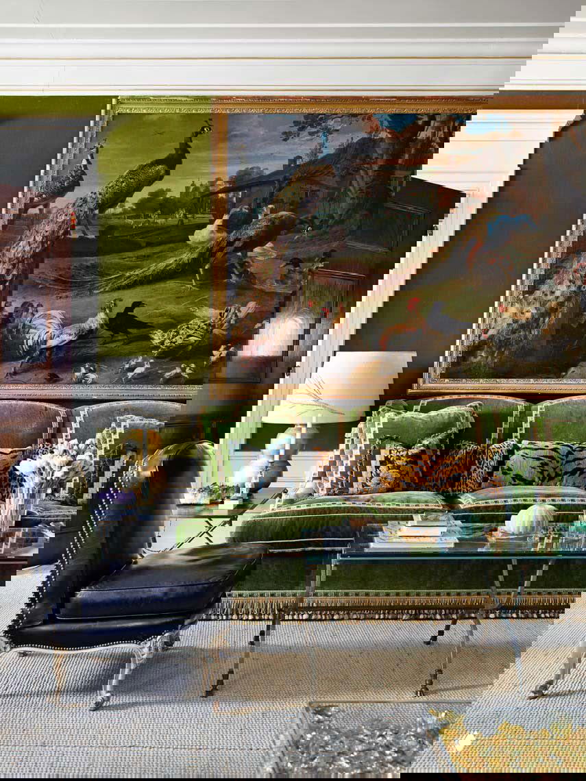 Зелёный велюровый диван с длинной декоративной бахромой в классическом интерьере; крупная картина и журнальный стол подчёркивают роскошную атмосферу.