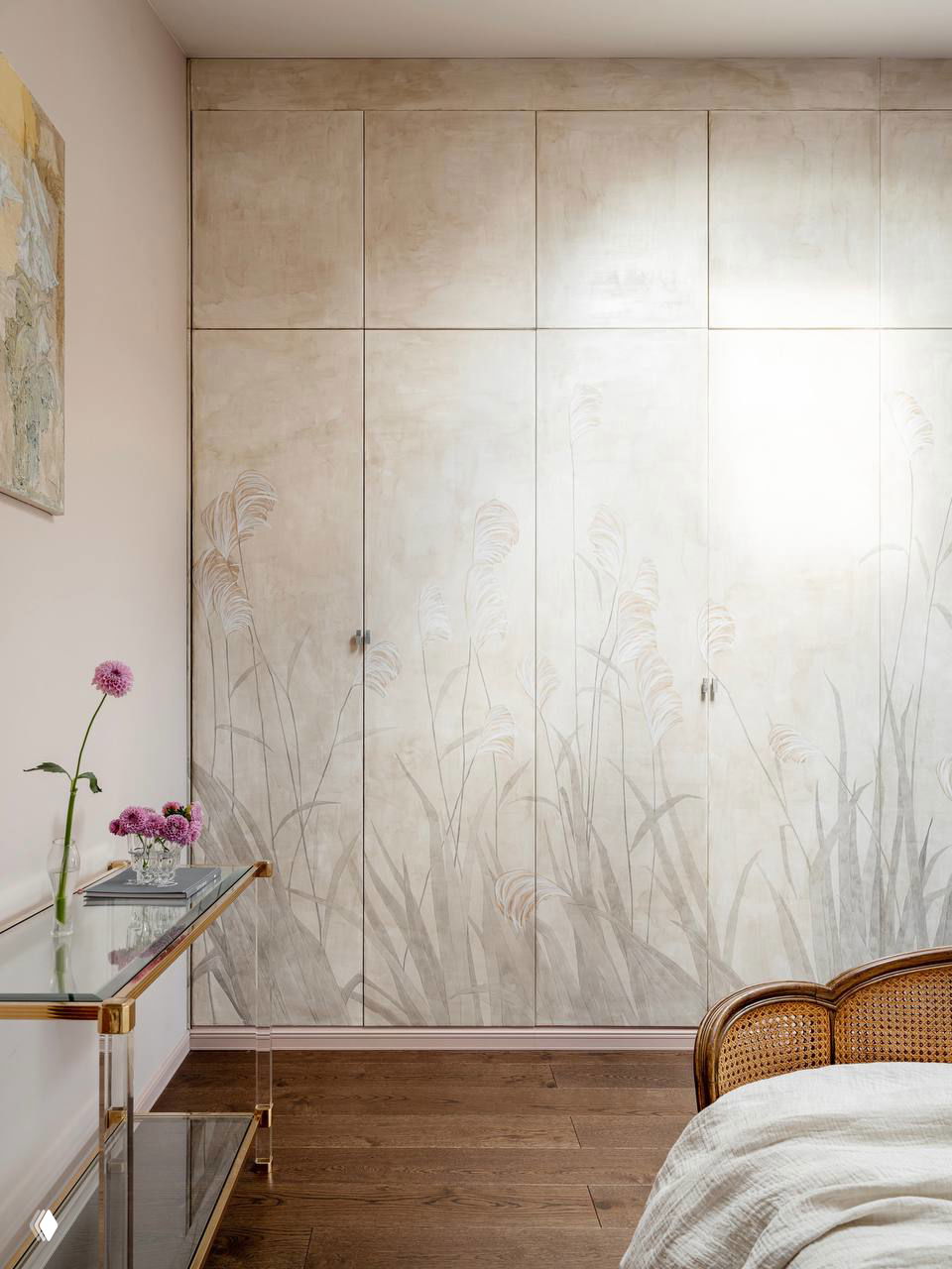 Светлый шкаф с деликатной фактурной отделкой и рисунком трав, гармонирующий с деревянным полом и нейтральной палитрой комнаты.