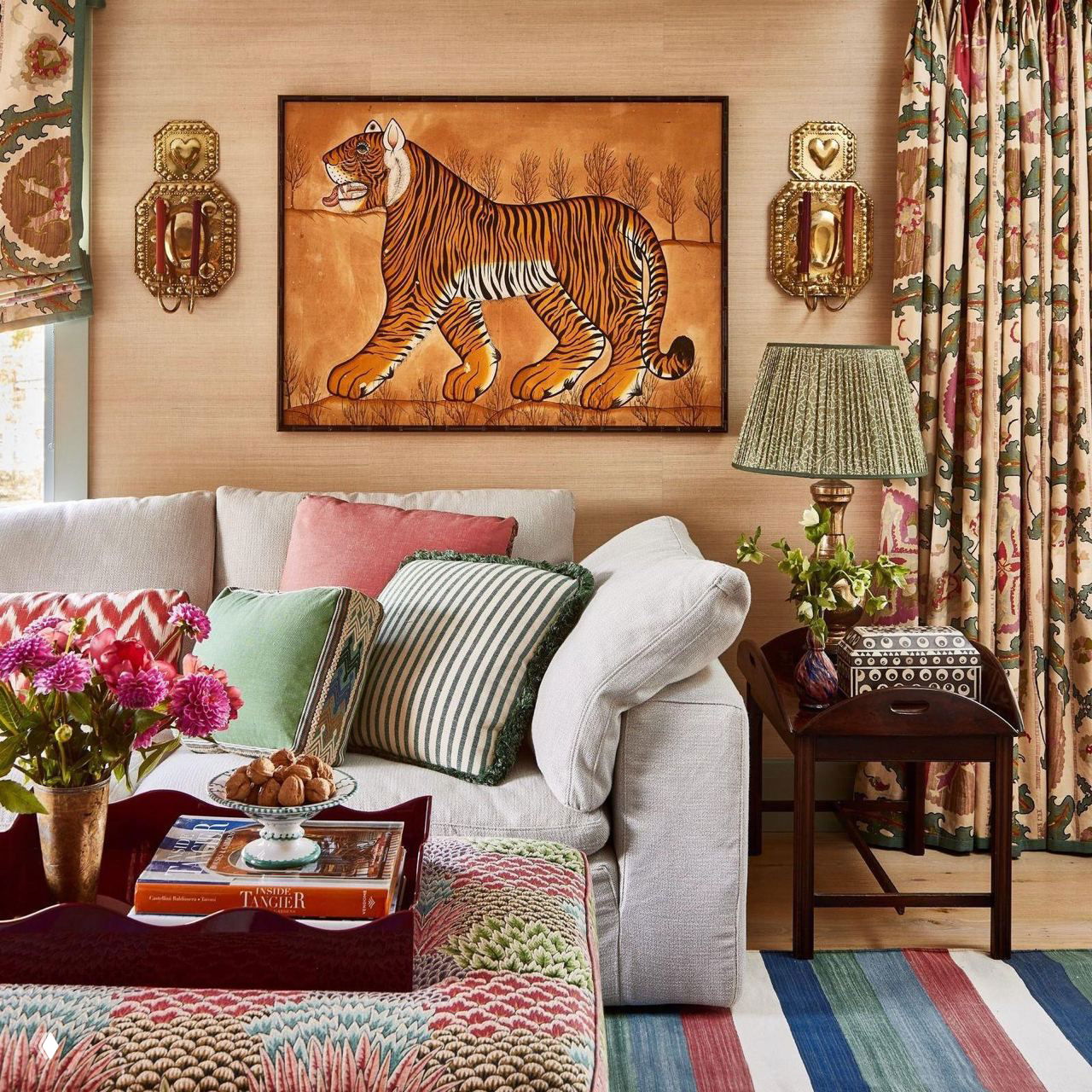 Гостиная с картиной тигра над диваном, множеством декоративных подушек и ярким текстилем в насыщенной палитре.