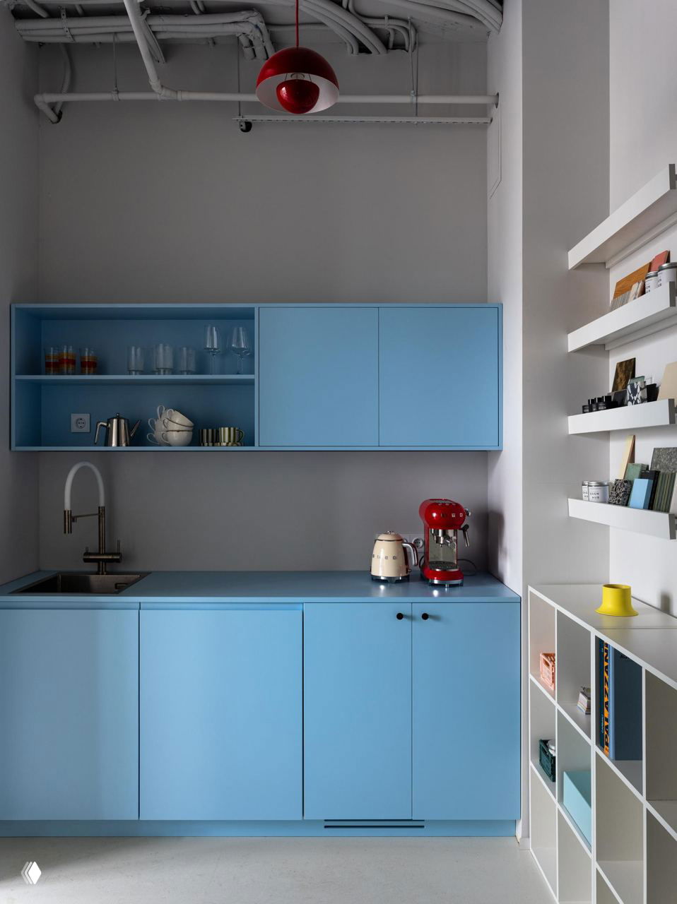 Кухонный блок в небесно-голубом оттенке с кофемашиной, чайником и минималистичными полками — практичный и яркий элемент офиса DSGN HUB.