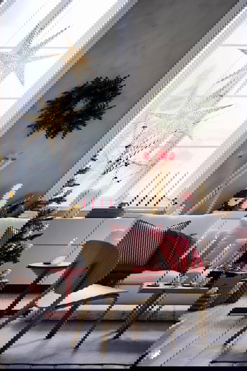 Интерьерная фотография: рождественская гостиная с белым диваном, декоративными подушками и заметной напольной лампой в форме больших спичек с красными головками.