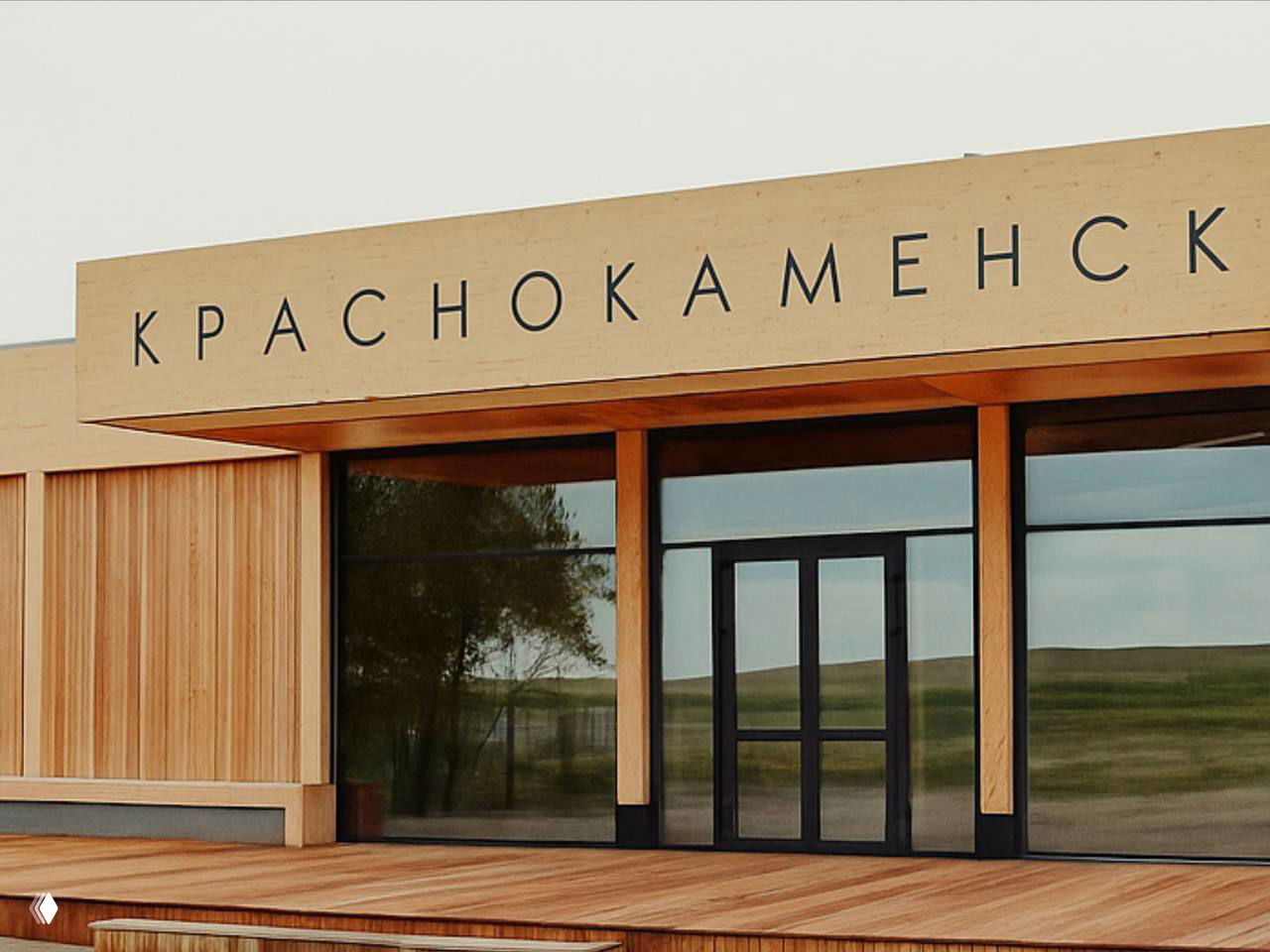 Фасад деревянного терминала аэропорта с крупной надписью «Краснокаменск»: современная деревянная архитектура, широкие стеклянные поверхности.