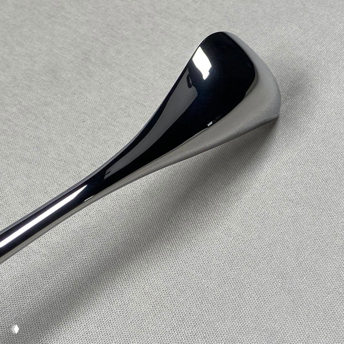 Деталь столового прибора крупным планом: гладкая полированная поверхность и эргономичная, изогнутая форма в стиле Zaha Hadid.