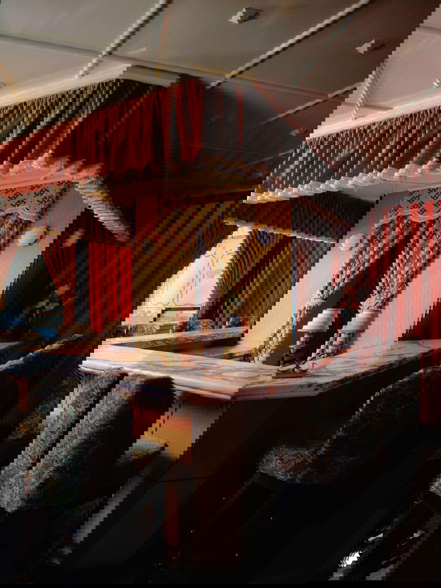 Барная зона с мраморной стойкой и девятью местами: мягкие стулья с узорной обивкой, карнизы с бахромой и театральные портьеры вокруг стойки.