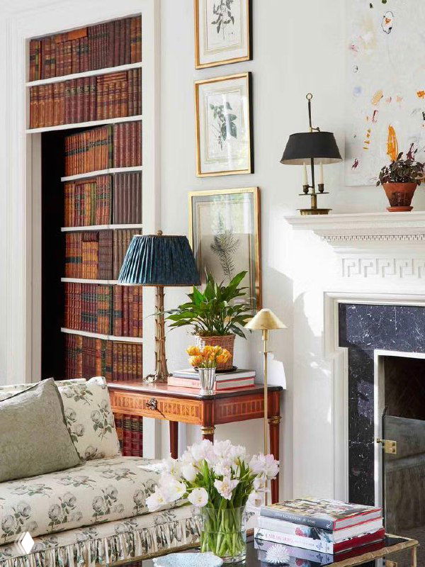 Фальш‑стеллаж с полками и книгами, маскирующий дверцы шкафа в классическом интерьере у камина и декоративного каминного портала.