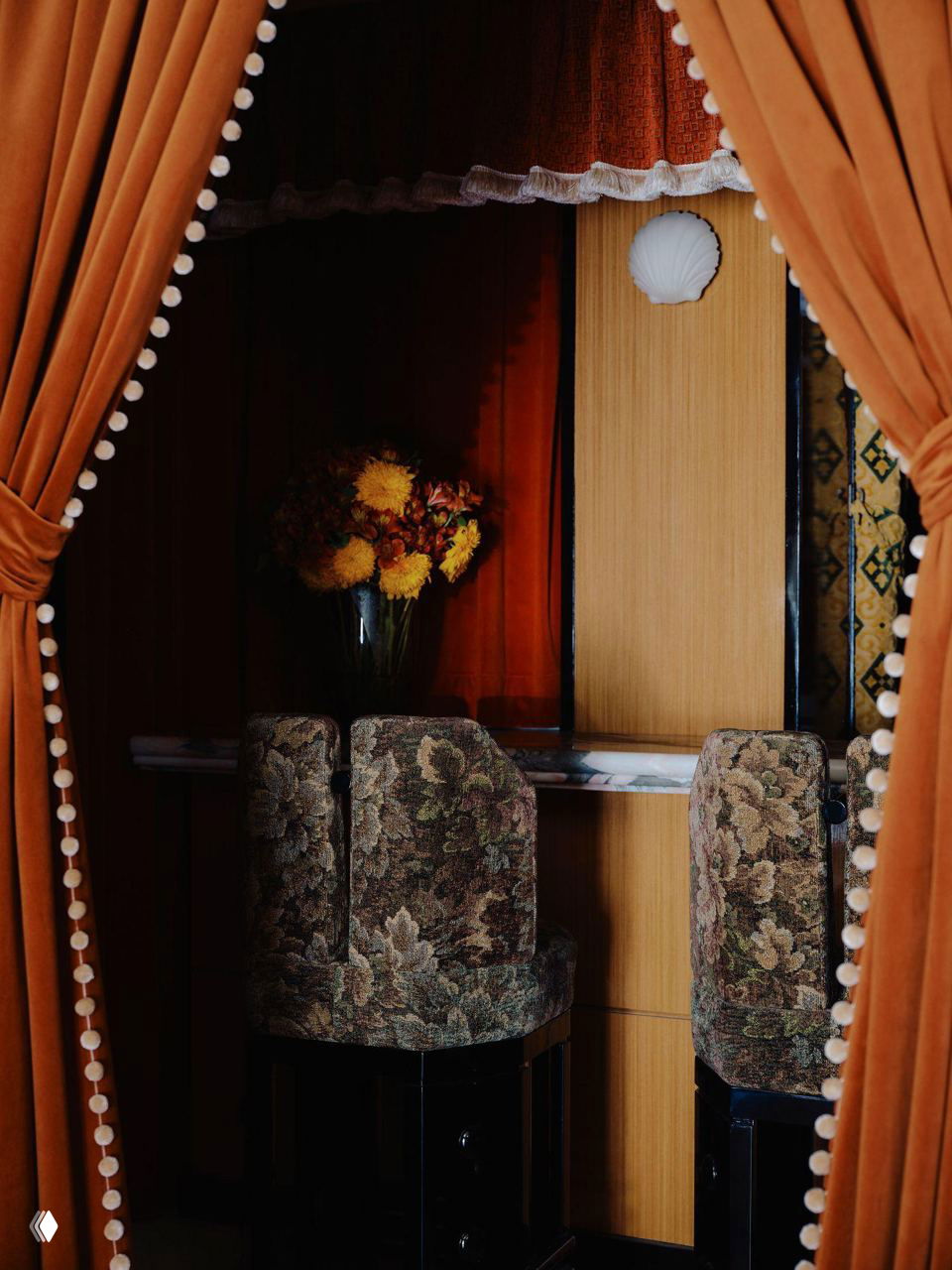 Ниша с мягкими диванами и маленькими столиками: тёплые охристые тона, узорные пуфы и картина над посадочной зоной в стиле ретро.