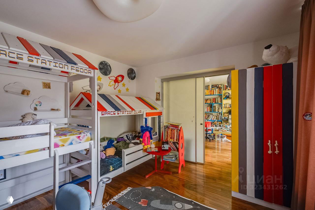 Детская комната с двухъярусной кроватью в тематическом оформлении 'space', красочным шкафом и множеством игрушек и учебных принадлежностей вокруг.