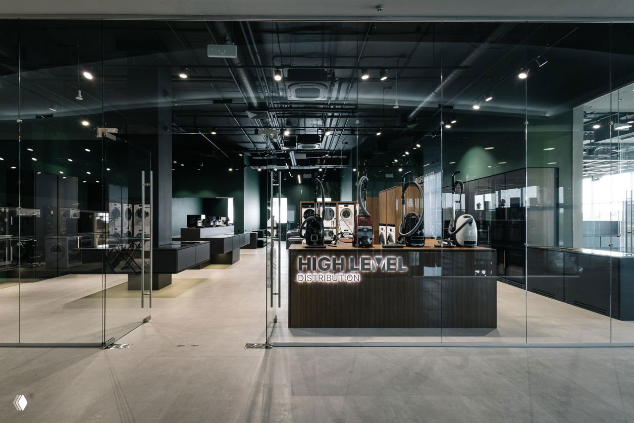 Витрина и вход в шоурум High Level в Casa Ricca Expo: стеклянный фасад, ресепшн с логотипом, экспозиция премиальной техники Asko и минималистичный интерьер.