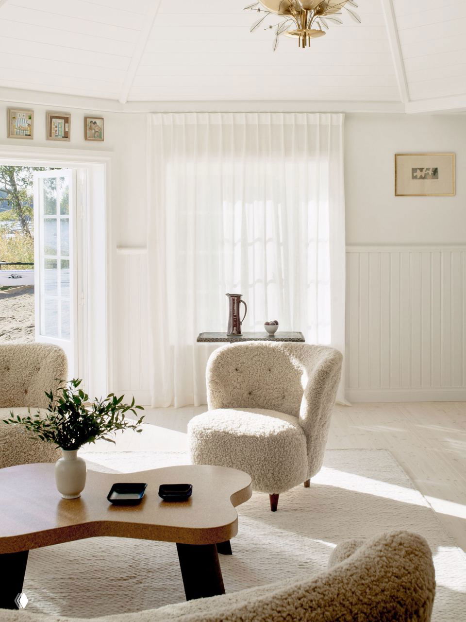 Уютная гостиная с бежевыми креслами и низким столиком на текстурном ковре: светлые шторы, много естественного света и минималистичная мебель.