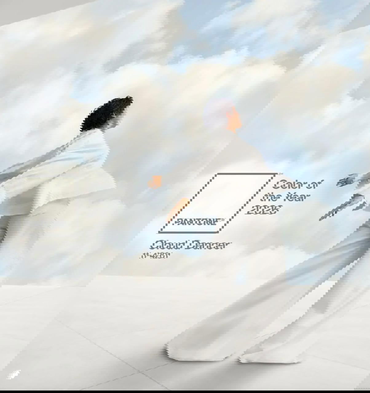 Рекламный визуал Pantone Color of the Year 2026: модель в белом костюме на фоне голубого неба с мягкими облаками и подпись Cloud Dancer.