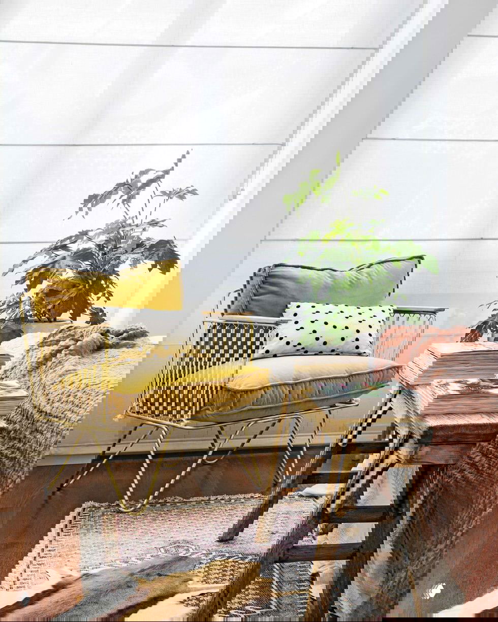 Сдержанная спальня с зелёными растениями на прикроватном столике и солнечным светом, спокойная палитра серых и бежевых тонов.