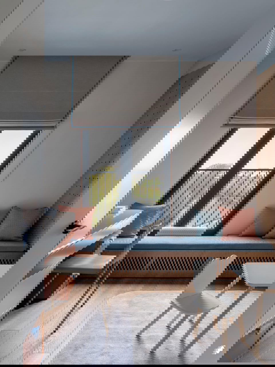 Рабочая и игровая зона у окна с мягкой скамьёй, рабочим столом и видом на реку — светлые деревянные полы и пастельные акценты в отделке.