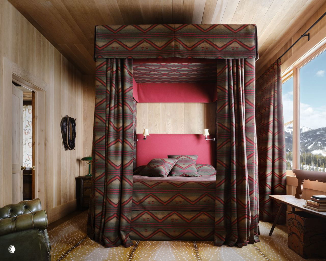 Спальня с балдахином: кровать, обтянутая тканью в геометрический орнамент, деревянные стены и потолок, текстиль в ковровых мотивах и вид на горы за окном.