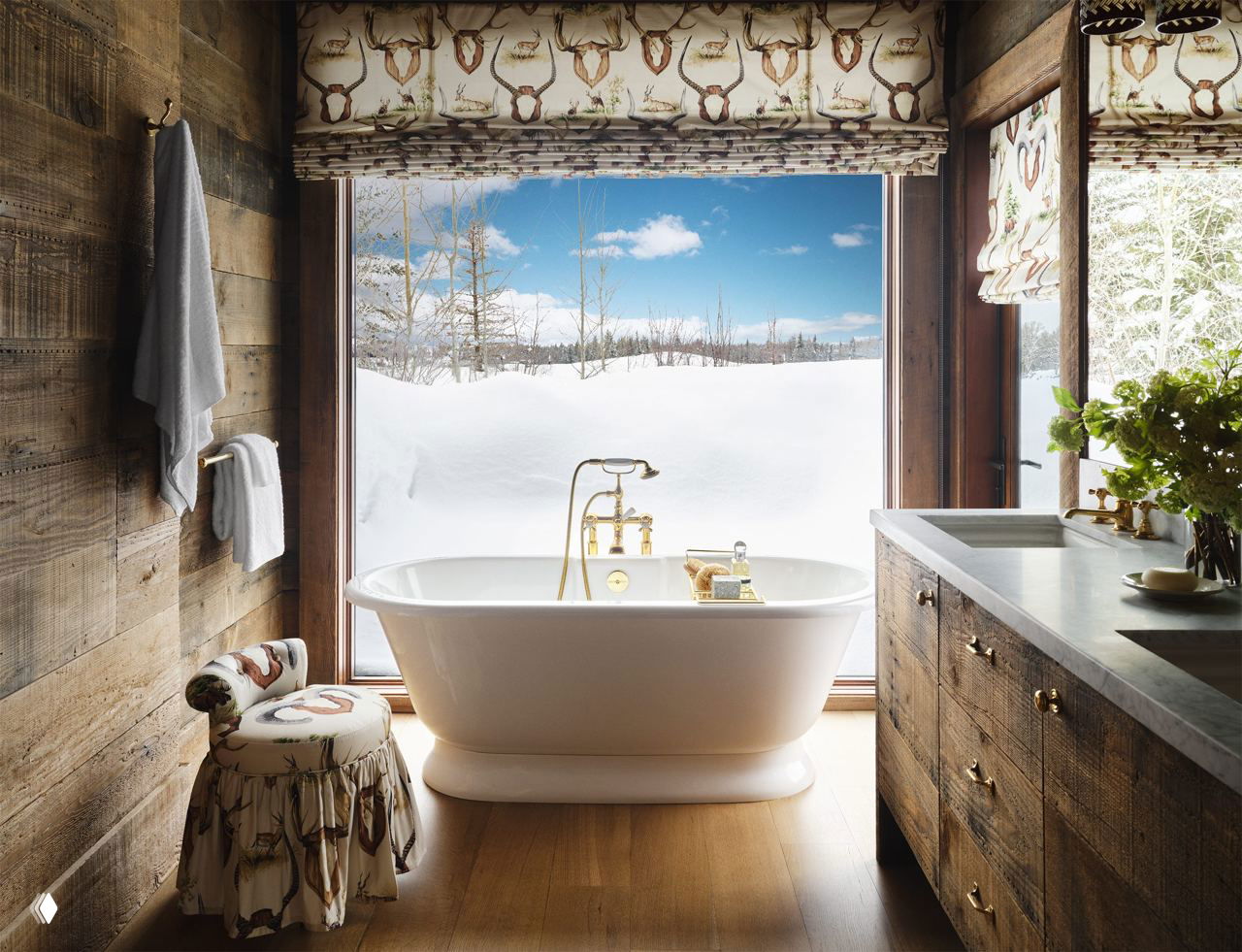 Ванная комната с отдельно стоящей белой ванной у большого окна: вид на заснеженный пейзаж, латунная сантехника и деревянная отделка создают атмосферу ранчо.