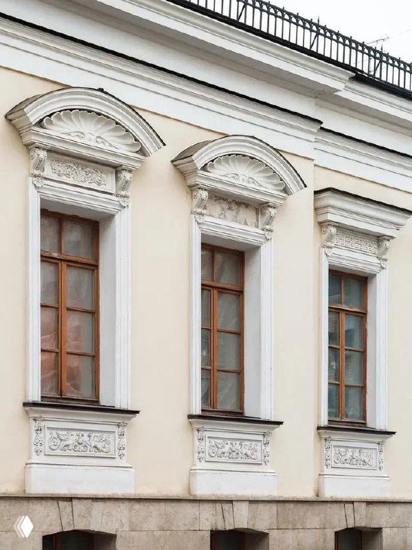 Фасад московской городской усадьбы конца XVIII века: три высоких деревянных окна с богатым лепным декором, пастельная штукатурка и каменный цоколь.
