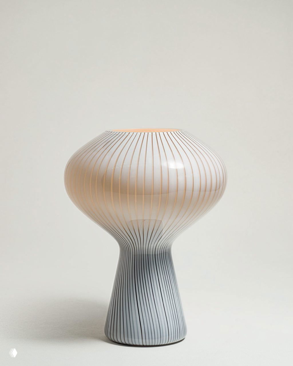 Керамическая или стеклянная грибовидная настольная лампа с тонкими вертикальными полосами, приглушённый свет и минималистичный фон.