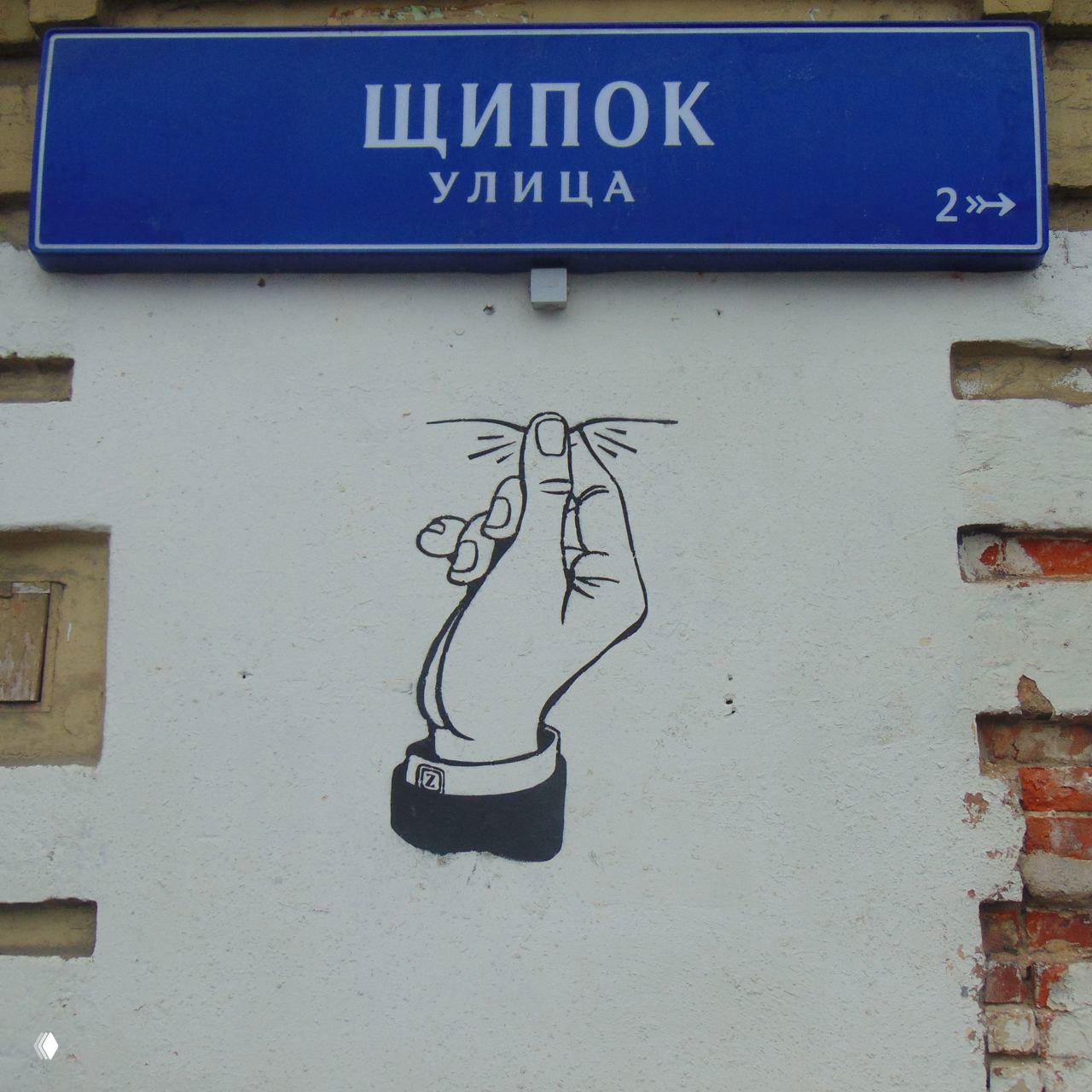 Уличная табличка с надписью «ЩИПОК УЛИЦА» на фасаде дома; под ней графическое изображение руки, символизирующее «щипок», городской пейзаж.