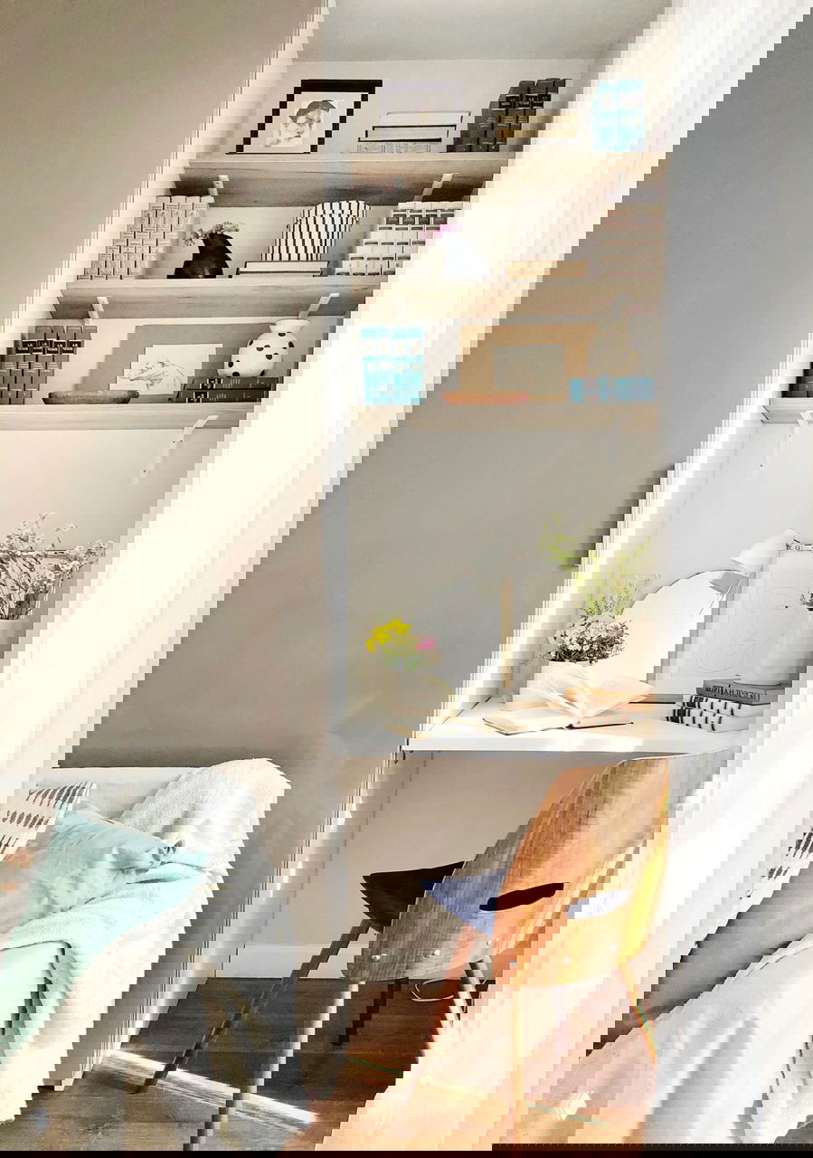 Рабочая зона в нише: компактный стол, стеллажи с книгами и стул — практичное решение для малой квартиры с хорошим дневным светом.