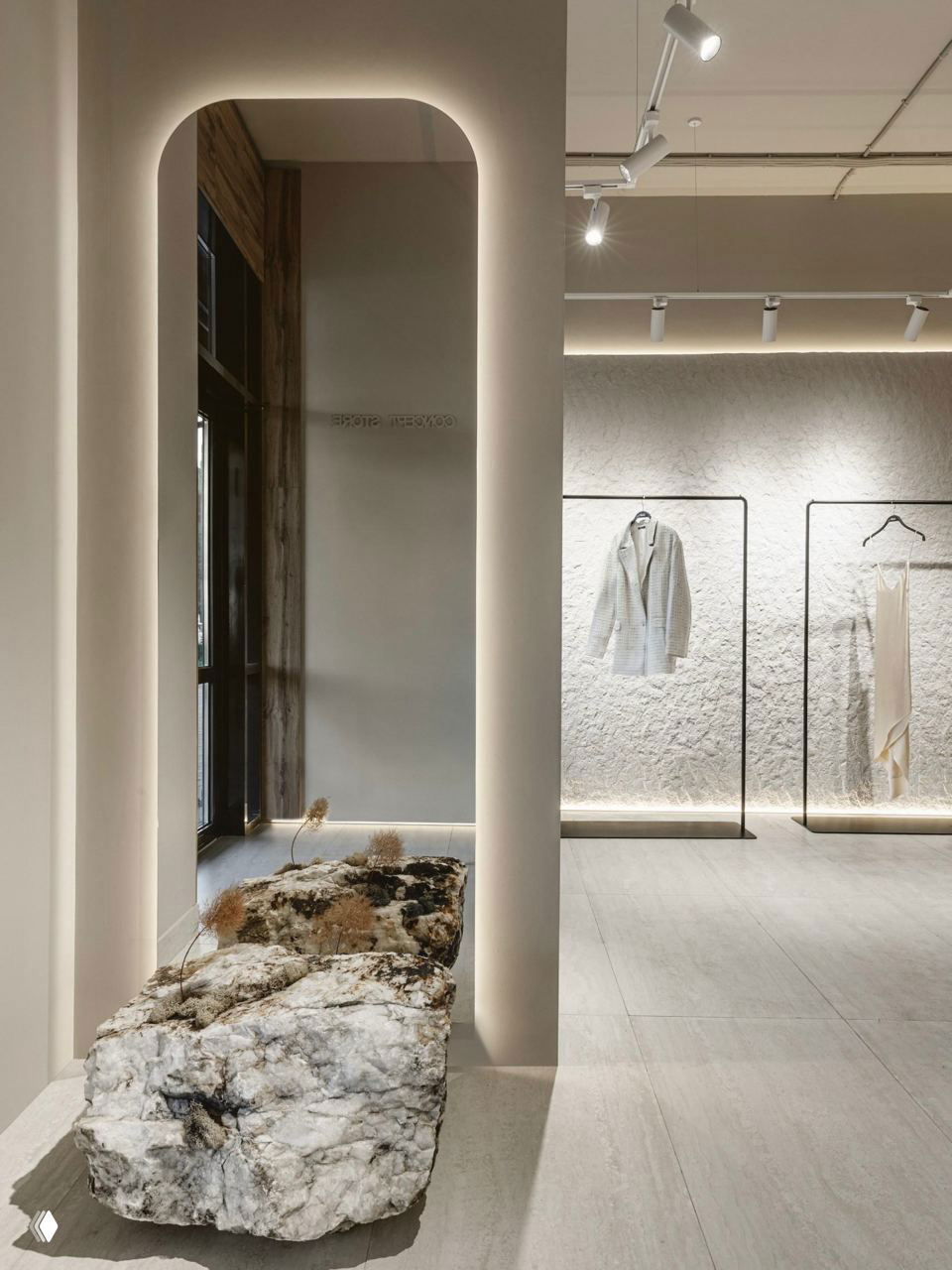 Арка в интерьере шоурума, мягкое прямое освещение, большая глыба камня, которая служит как декоративный элемент и акцент в проходной зоне.