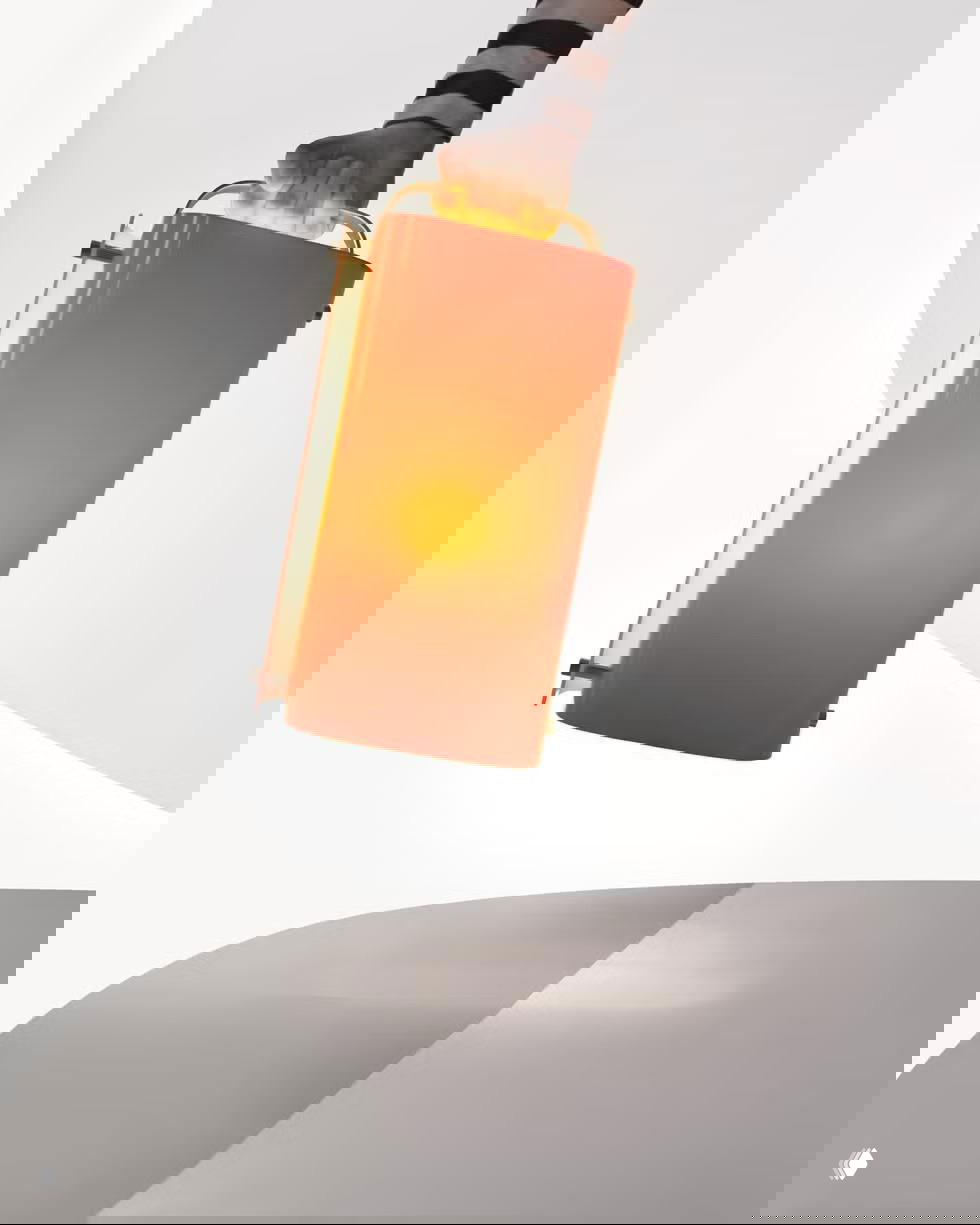 Портативная прямоугольная лампа с ручкой в оранжево-красном корпусе, дизайн с акцентом на форму и удобство переноски.