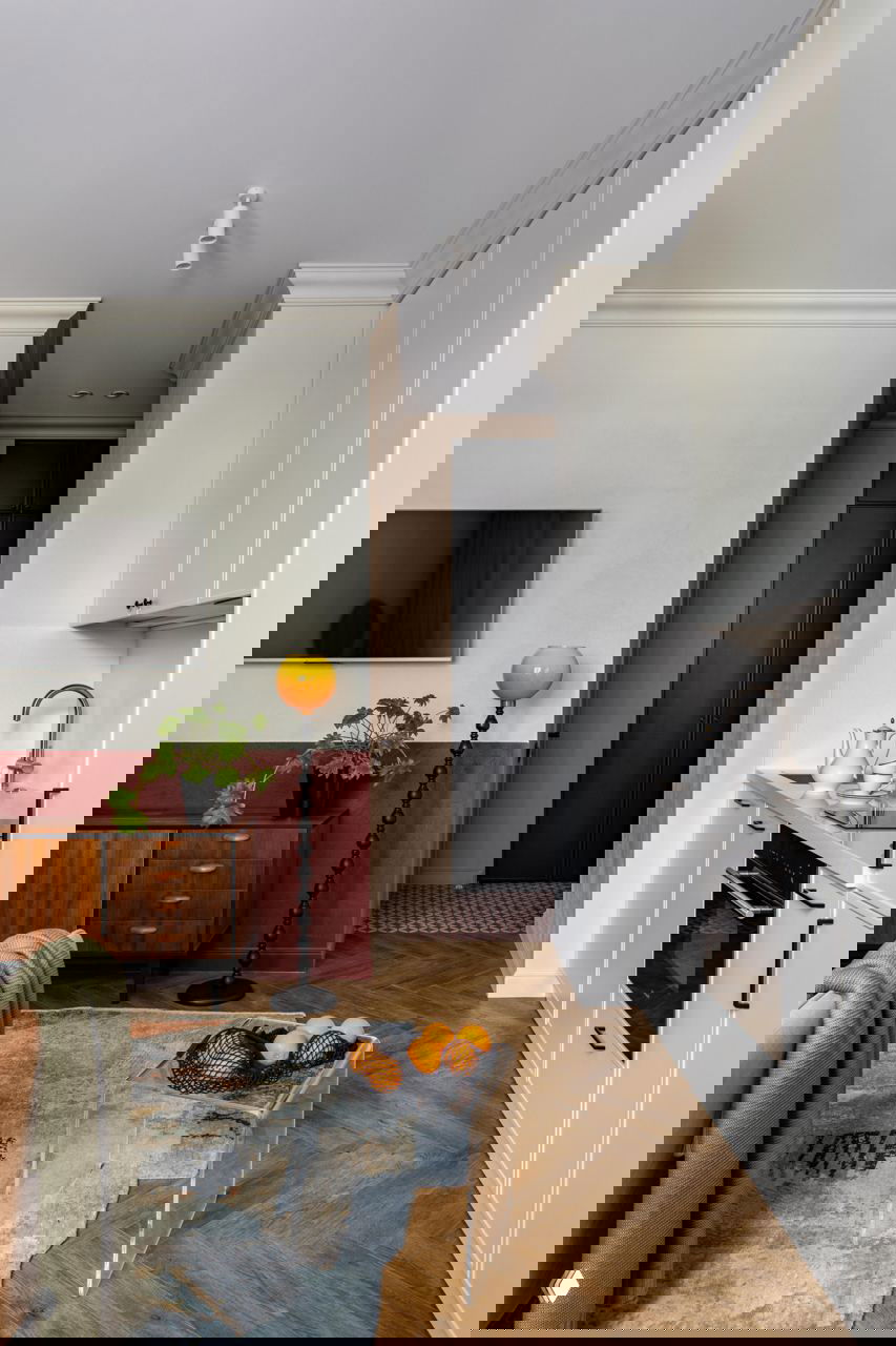 Вид на гостиную и кухню: низкая мебель в винтажном стиле, прозрачный акриловый стол и декоративные предметы, подчёркивающие красочно-винтажную палитру интерьера.