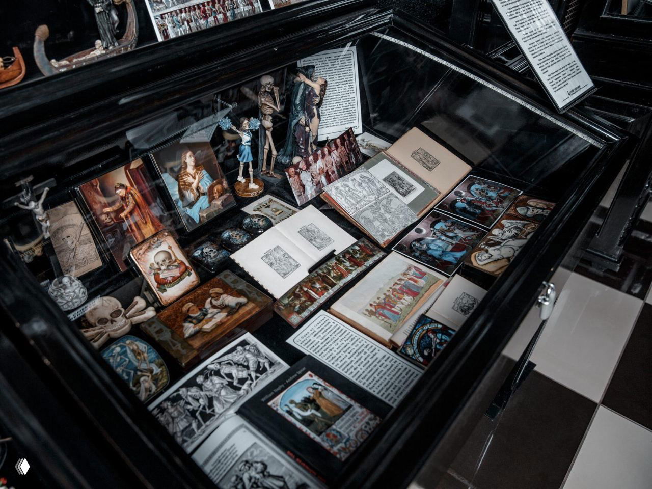 Витрина с миниатюрами, гравюрами, открытками и иллюстрациями погребальной тематики в экспозиции Музея смерти в Новосибирске.