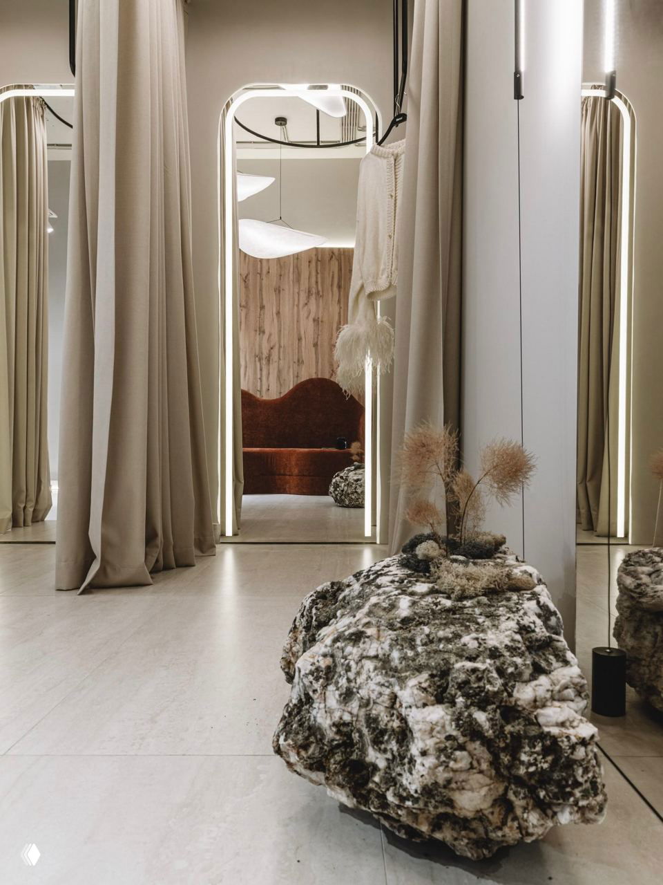 Зеркала и примерочная в бутике Blanco: большие зеркальные порталы, светлые шторы и массивная бело-серая глыба камня на переднем плане, декор из сухоцветов.