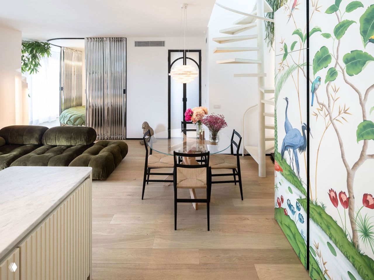 Общий вид открытой зоны: диван зелёного оттенка, стеклянный стол и светлая деревянная доска пола на фоне декоративной ширмы с изображением журавлей.