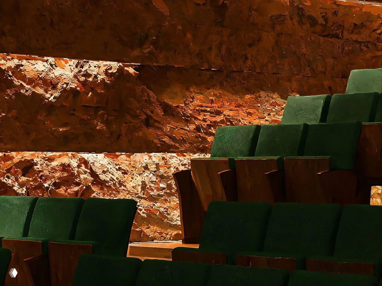 Ряды зелёных кресел и декоративная каменная стена в зрительном зале, детали отделки и сочетание текстур материалов.