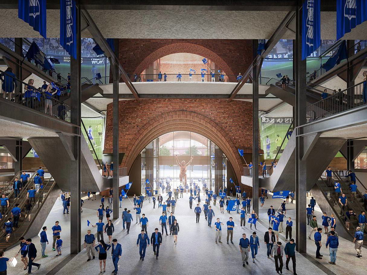 Вестибюль стадиона с кирпичными арками и потоками людей в клубных цветах, показывающий внутреннюю «вертикальную гостиную» и общественные пространства.