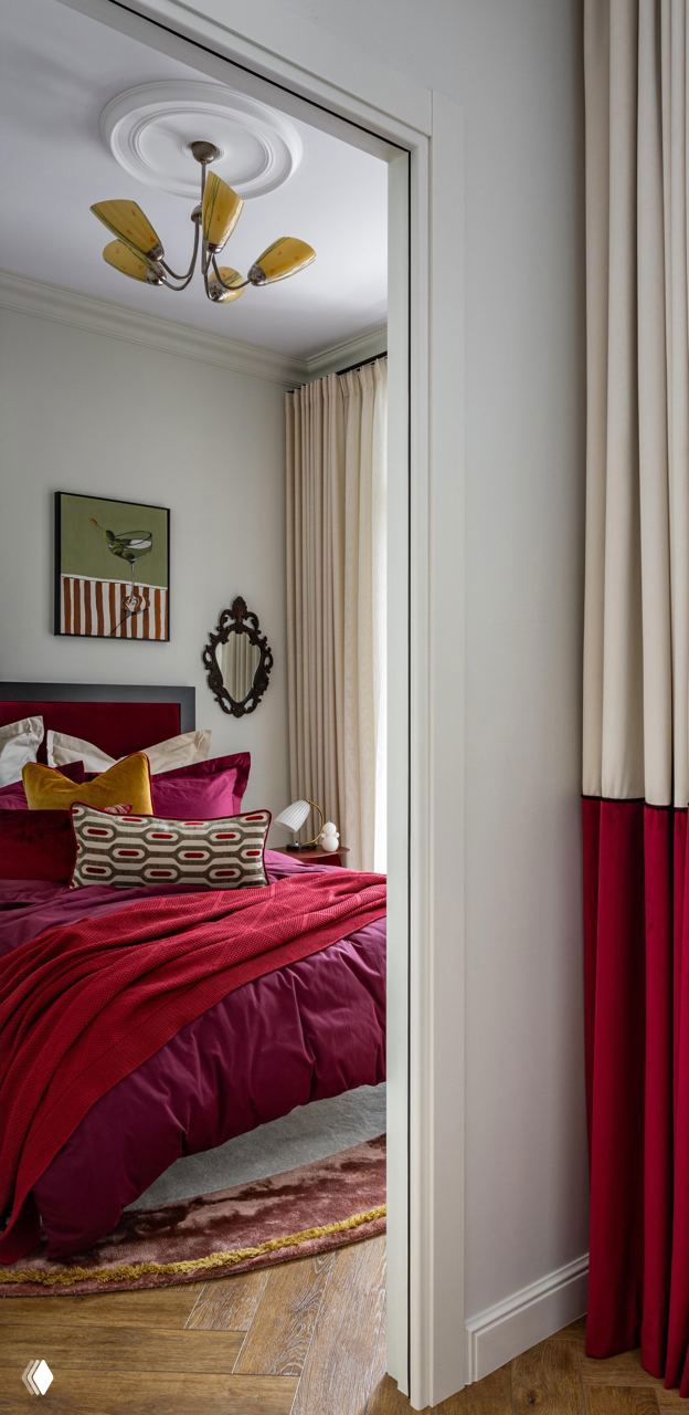 Спальня с насыщенными бордовыми и вишнёвыми текстилями: кровать, набивные подушки, шторы в два тона и мелкие декоративные предметы в стиле mid-century.