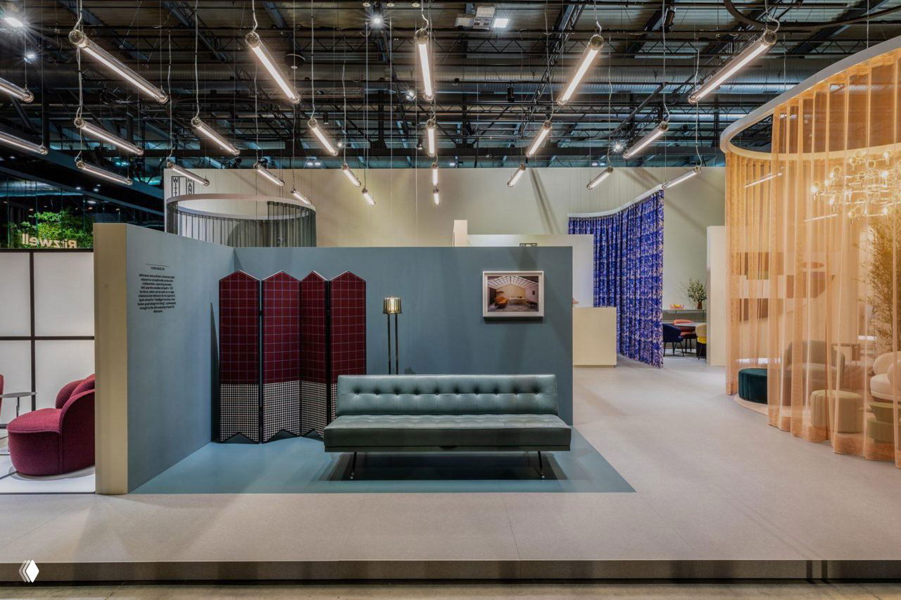 Интерьерный стенд Salone del Mobile в Эр-Рияде: зелёный диван, складная ширма, напольный торшер и стилизованная экспозиция в павильоне выставки.