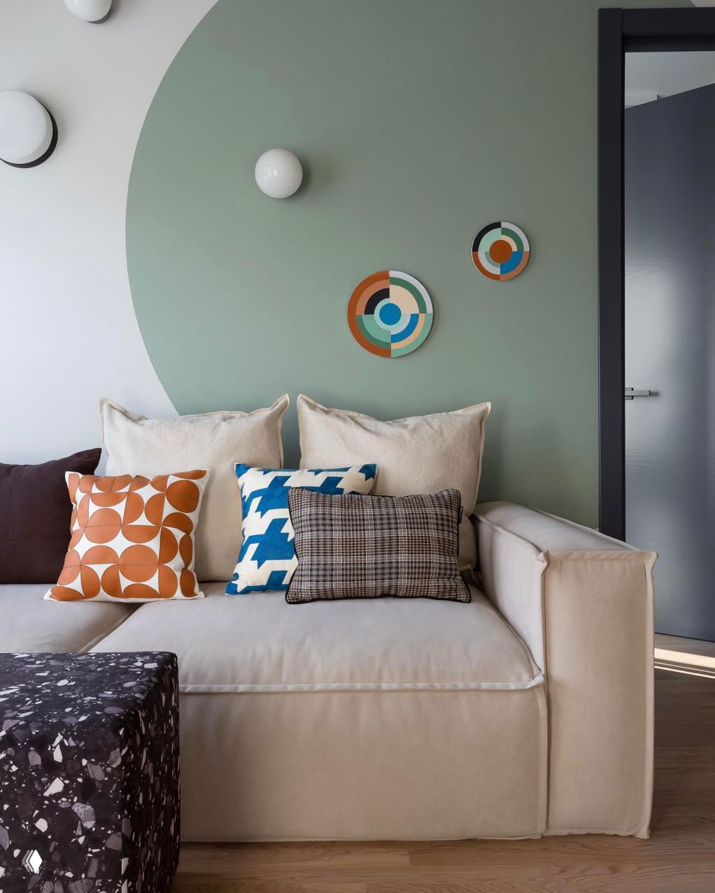 Гостиная с большим полукруглым зелёным фрагментом стены близкого к васаби оттенка, нейтральный диван и разноцветные декоративные подушки создают яркий акцент.