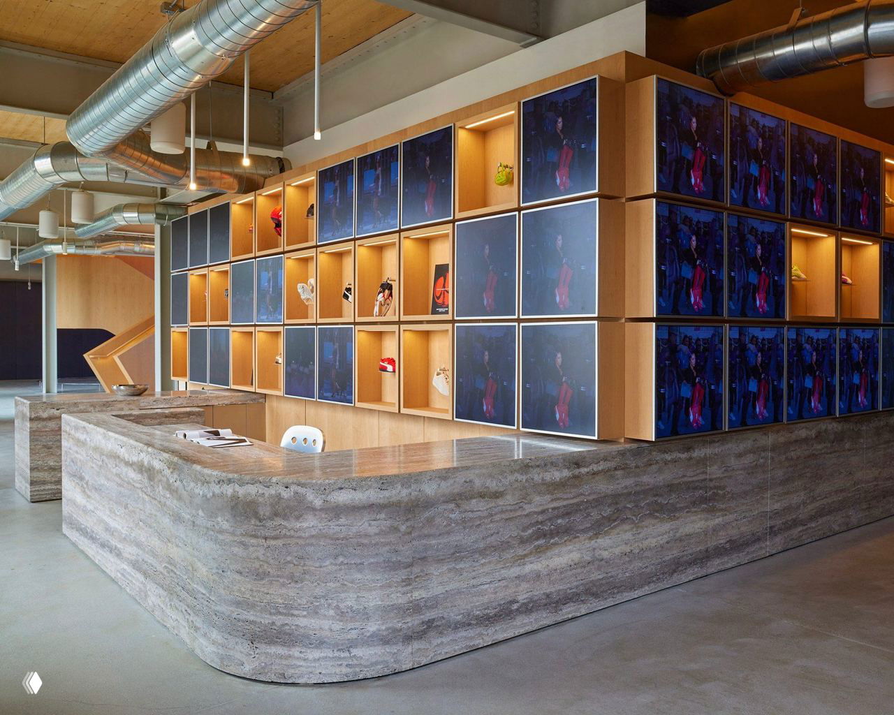 Ресепшн и модульная экспозиция: массивная стойка из камня, деревянные ниши с экранами и аккуратная индустриальная отделка с видимыми воздуховодами.