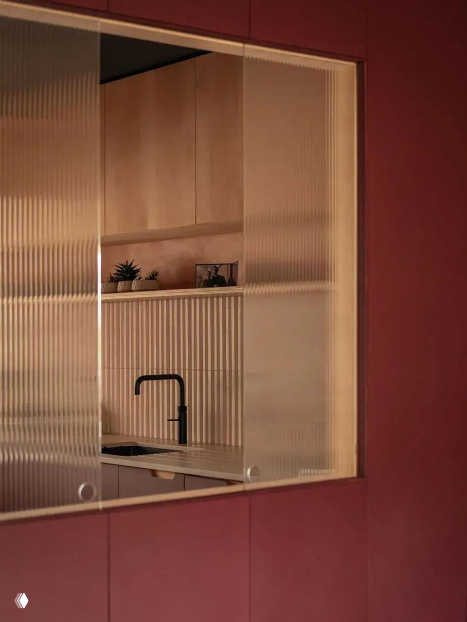 Прямоугольный кухонный проём с окном над мойкой, растения и нейтральная отделка создают уютный вид между зонами