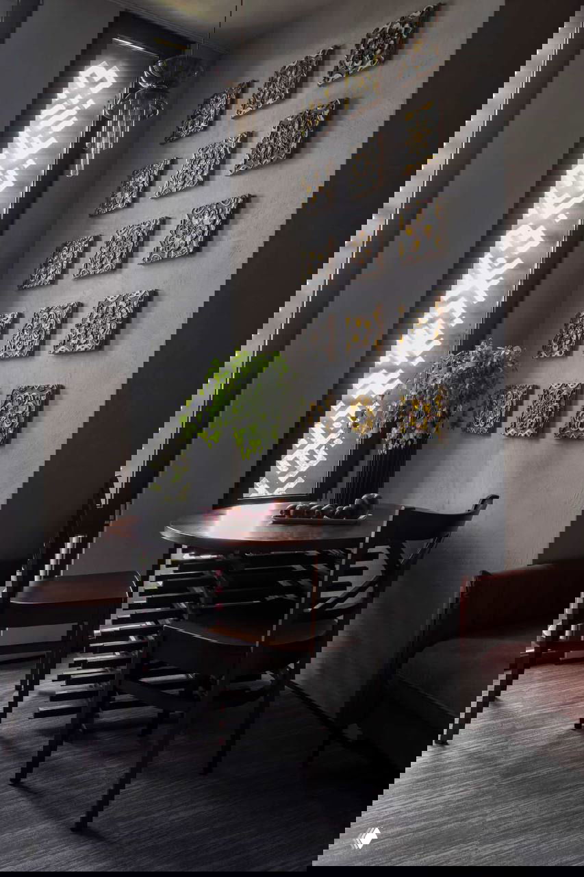 Уютный угол с круглым столом и декоративными керамическими панелями на стене; сочетание тёплых оттенков и традиционной орнаментики.