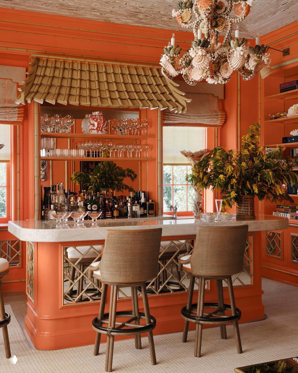Коралловый домашний бар с мраморной столешницей, ротанговыми барными стульями и декоративной ракушечной люстрой в интерьере Палм‑Бич.