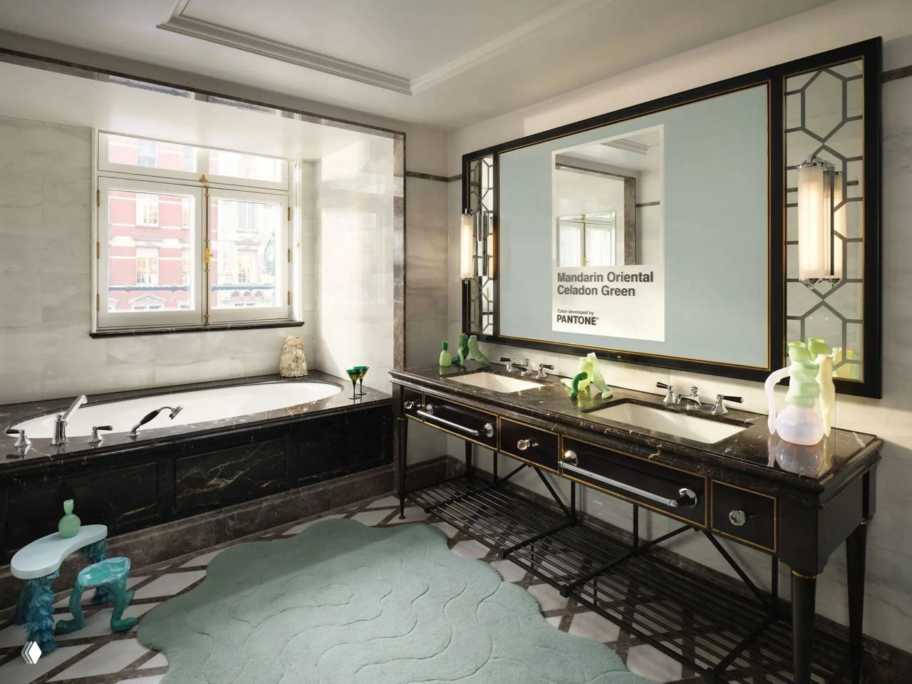 Санузел люкса Mandarin Oriental: мраморная облицовка, чёрные раковины и коврик Celadon Green, в зеркале надпись Pantone Celadon Green.