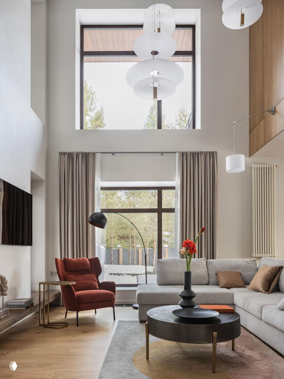 Современная гостиная с угловыми окнами, большими шторами, светлой мягкой мебелью и видом на город через застеклённую часть стены.