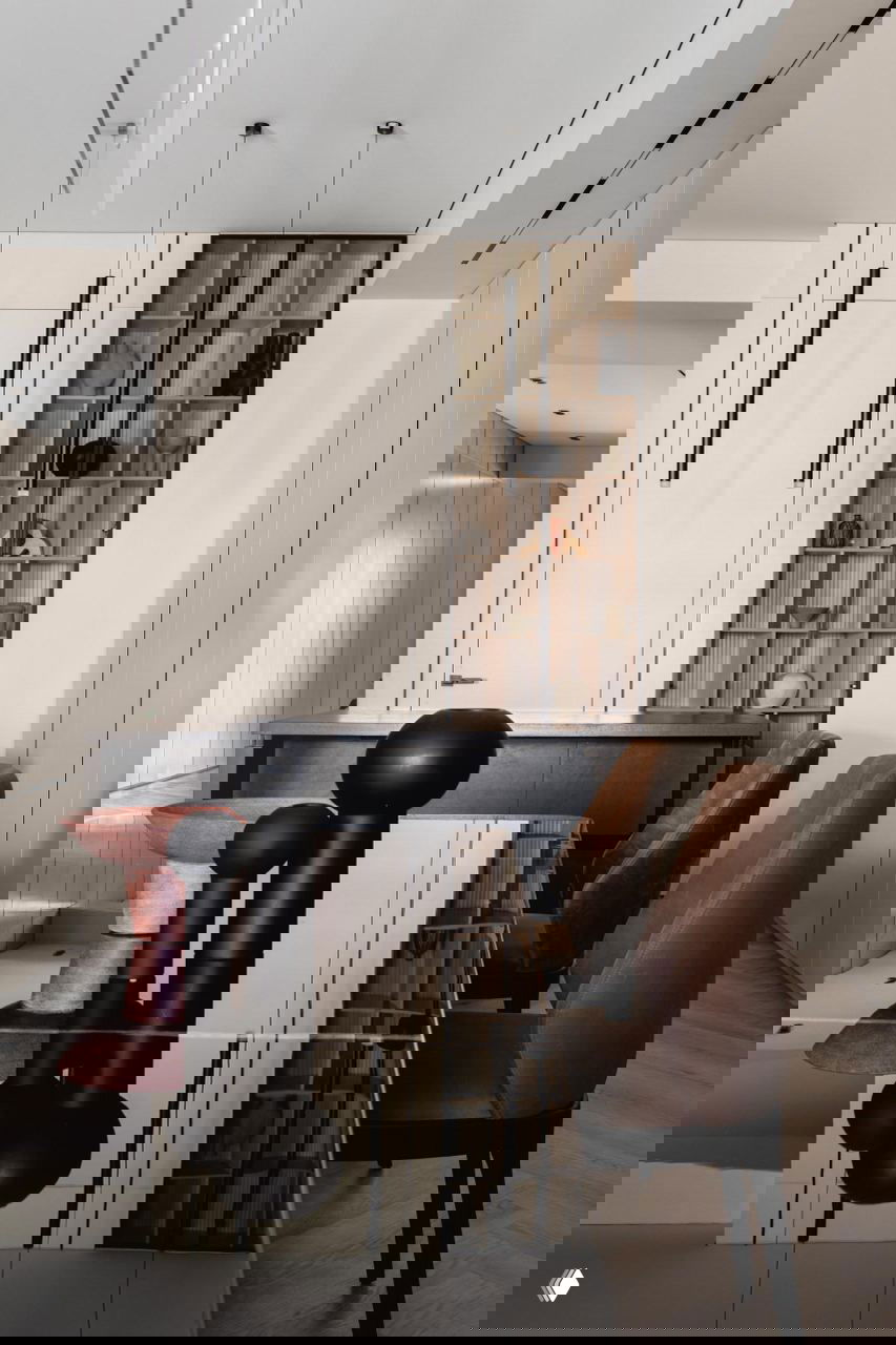 Интерьер столовой с отражающей чёрной столешницей, матовыми чёрными вазами и коричневыми стульями на фоне бежевых панелей и полок в проекте Жанны Бондаренко.