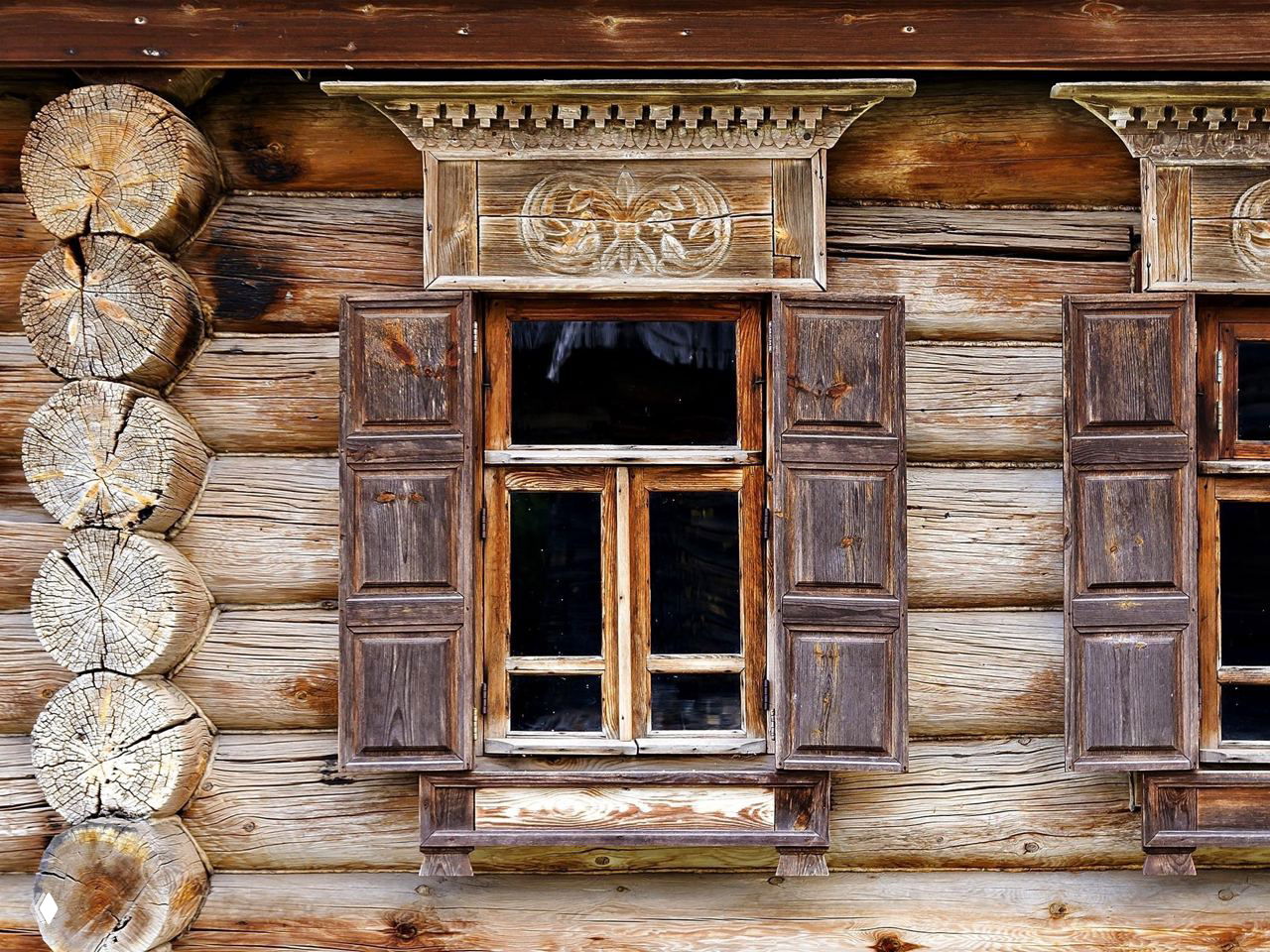 Деревянный фасад с резными наличниками и ставнями, крупный план традиционного архитектурного декора суздальских домов и мастерства плотников.