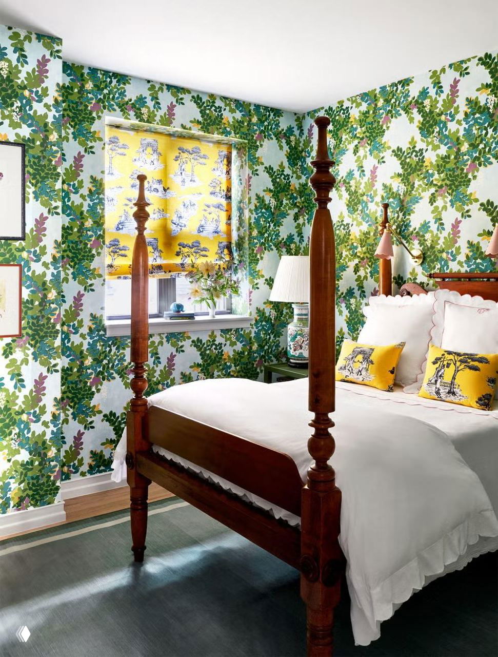 Спальня с зелёными растительными обоями по стенам, деревянная четырёхстоечная кровать, белое постельное бельё и жёлтые декоративные подушки в рисунок.