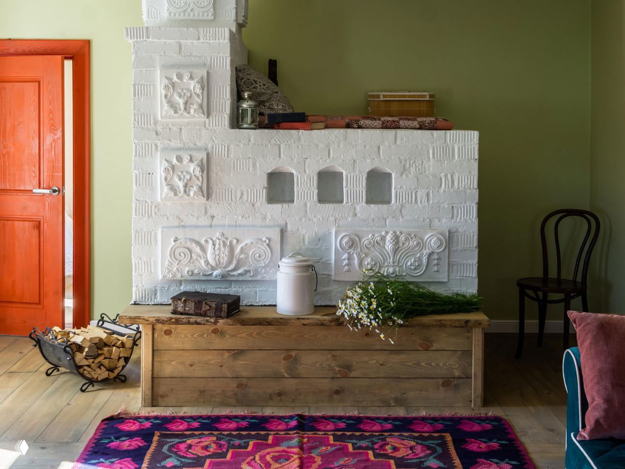 Интерьер традиционной русской печи и деревянной скамьи с цветочным ковром, элементы декора в уютной деревенской комнате в суздальском стиле.