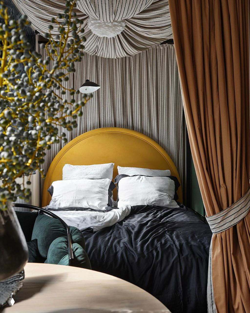 Роскошная мини‑спальня с полукруглым изголовьем ярко‑горчичного цвета, драпировки над кроватью и природные текстуры в интерьере для камерной атмосферы.