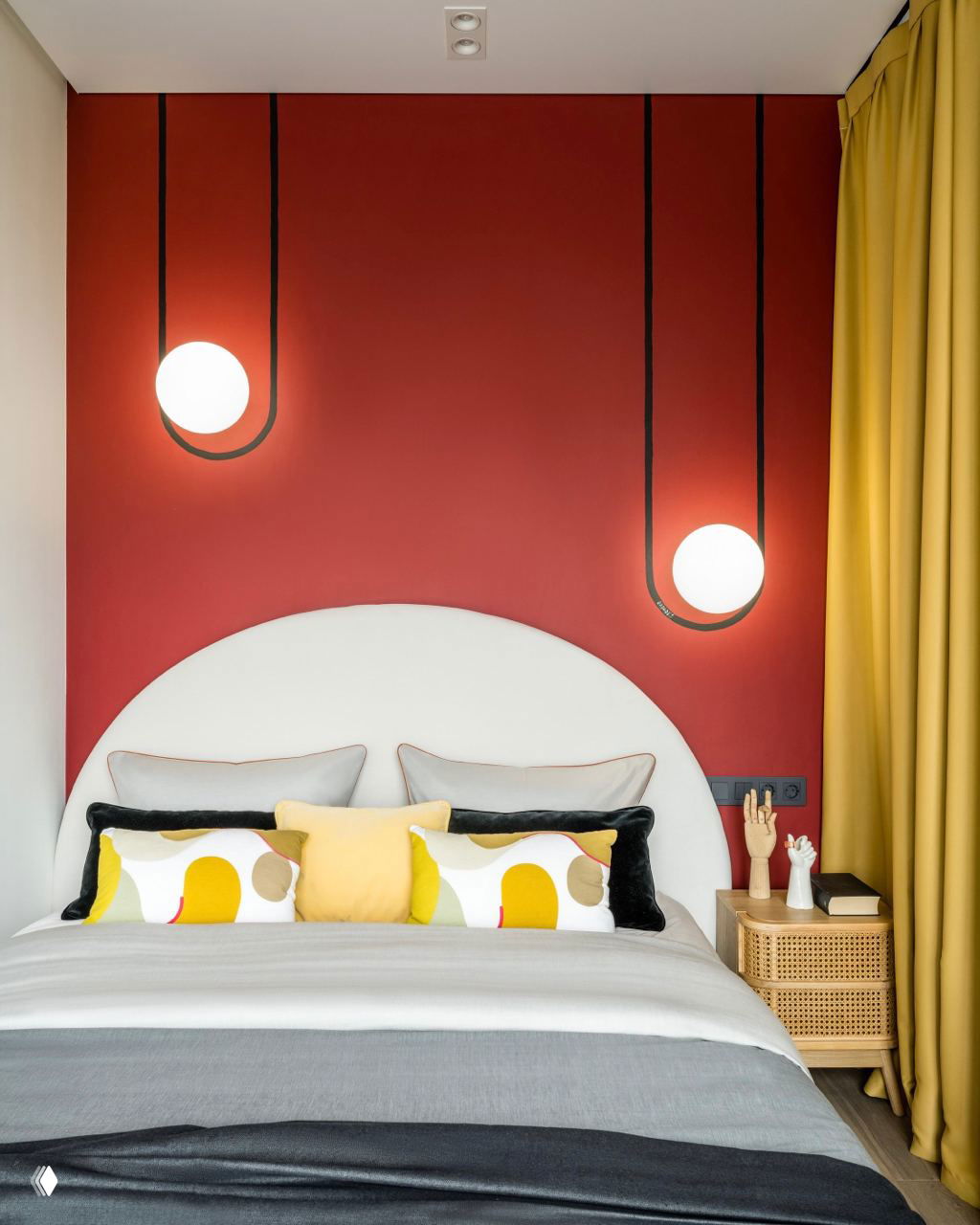Современная компактная спальня с акцентной ярко‑красной стеной и подвесными светильниками, декоративные подушки и шторы жёлтого оттенка усиливают цветовой контраст.