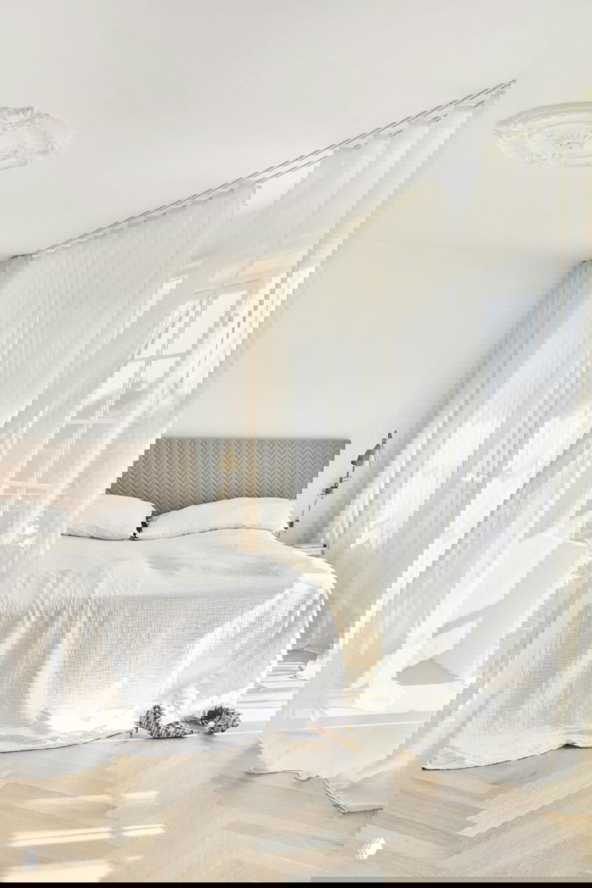 Спальня с белым текстилем, светлым паркетом и воздушными шторами: спокойный скандинавский интерьер в доме Аннет Кьерульф.