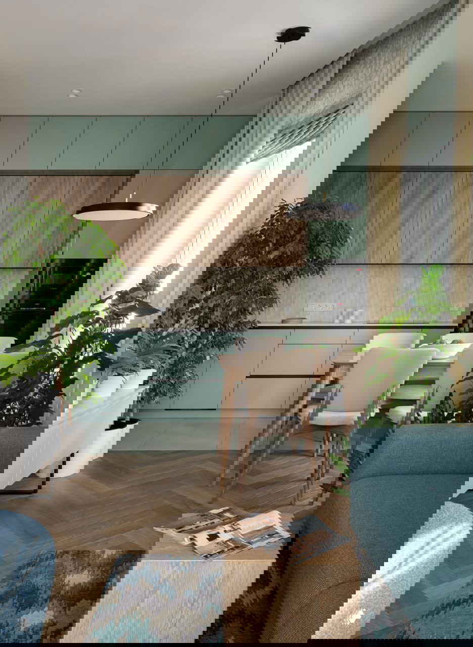 Кухня-столовая с мятными фасадами и деревянными акцентами, обеденный стол и крупные комнатные растения по краям пространства для уюта.