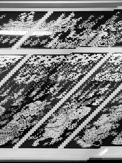 Несколько панелей вытынанок на тёмном фоне с изображениями Деда Мороза, игрушек и гирлянд, плотная композиция праздничных вырезок.