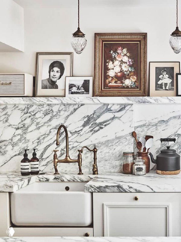 Кухонная зона с мраморной столешницей, медным смесителем и декоративными рамками на полке — пример элегантного оформления и хранения на рабочей зоне.